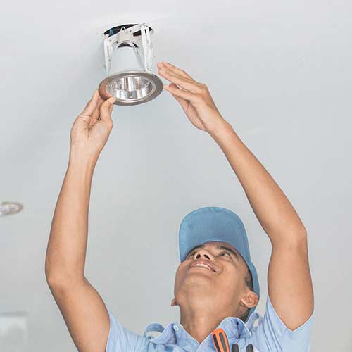 Electrician installing interior lighting fixtures